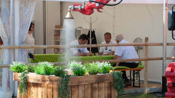 Demonstration einer Bewässerungslösung auf der demopark. Wasser wird über eine Düse auf eine bepflanzte Ausstellungsfläche verteilt, während Fachbesucher im Hintergrund Gespräche führen
